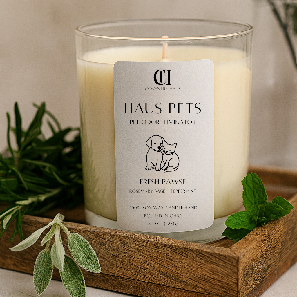 Candle labeled 'Haus Pets' on a wooden tray with greenery
