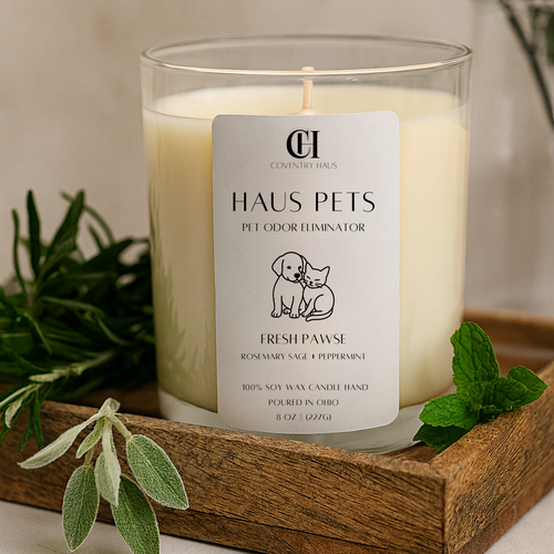 Candle labeled 'Haus Pets' on a wooden tray with greenery